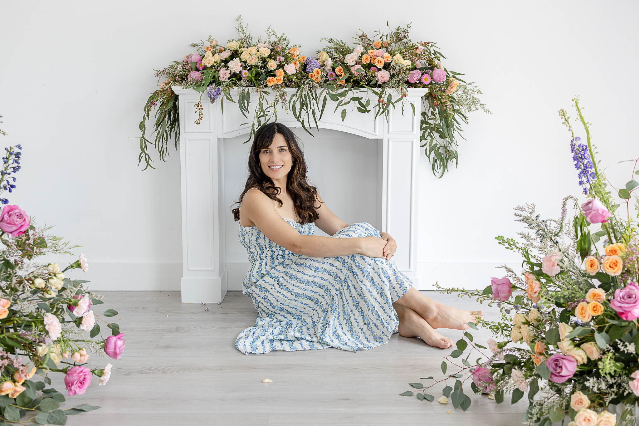 Susana Stethers seated beneath a colorful floral installation